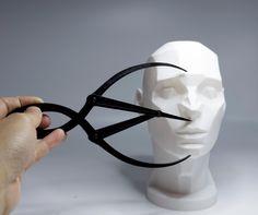 a person is holding scissors to the face of a white mannequin's head