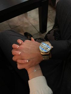 a person sitting on the ground with their hands clasped to each other, wearing a watch