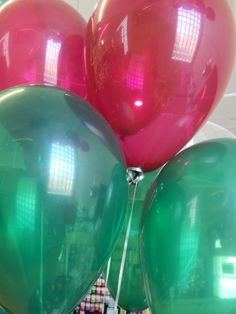 several large balloons are in the air with some string attached to them and one balloon is pink and green