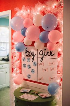 a baby shower sign with balloons and streamers hanging from the wall in front of it