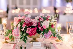 a table set with pink and white flowers in a gold vase on top of it