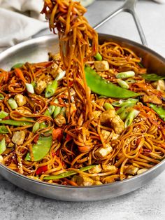 someone stir frying noodles with vegetables in a wok