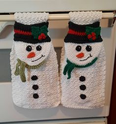 two white towels with snowmen on them are hanging from the oven door, and one is wearing a green scarf