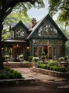 a large green house with lots of windows and plants on the front lawn, surrounded by trees