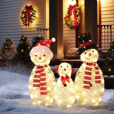 two snowmen standing in front of a house decorated for christmas