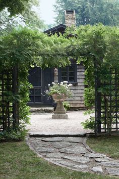 a stone path leads to a house through an iron gate with flowers in the center