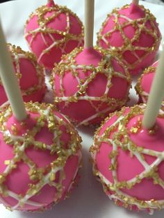 pink cake pops with gold sprinkles on a white plate