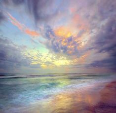 the sun is setting over the ocean with clouds in the sky and water on the beach