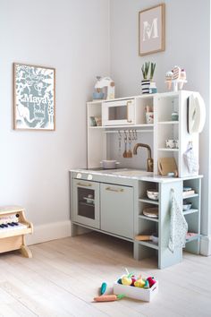 a child's play kitchen with toys on the floor and in front of it