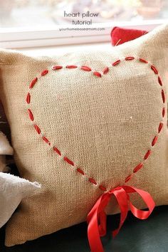 a heart pillow sitting on top of a window sill next to a red ribbon