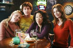 three women and one man sitting at a table in a bar with beer glasses on it