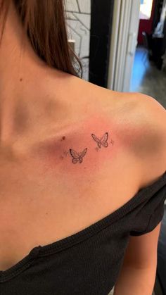 a woman's shoulder with two butterflies on the left side of her chest,