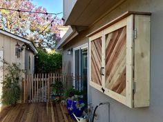 a wooden deck in front of a house with potted plants on the outside wall