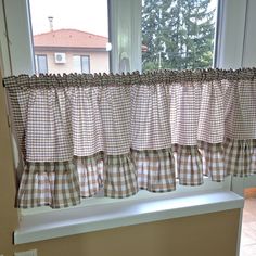 a kitchen window with checkered curtains in front of it