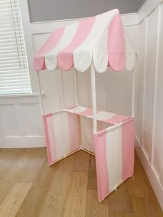 a pink and white tent sitting on top of a wooden floor next to a window