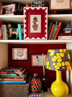 a yellow lamp sitting on top of a table next to a shelf filled with books