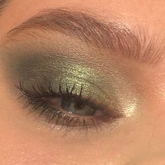 a woman's eye with green eyeshadow and gold foil on the lashes