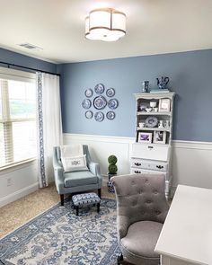 a living room with blue walls and white trim on the walls, two gray chairs in front of a large window