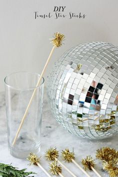 a disco ball next to a glass with gold glitter on it and two straws