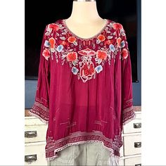 New With Tags Size Medium This Beautiful Wine Colored Blouse By Johnny Was Has A Japanese Floral Theme. The Oversized Bohemian Blouse Has A Scoop Neck & Is Covered In Intricate Embroidery. There Is White Wave Embroidery Along The Hem And Sleeves. The Bodice Is Covered In Vibrant Flowers And At The Center Is A Whimsical Scene With Two Geishas Under An Umbrella. The Top Is A Pullover Style Made From 100% Cupra Rayon. Measurements Laying Flat: Length 25.5” Bust 25” Festive Bohemian Top With Embroidered Sleeves, Bohemian Tops With Embroidered Sleeves For Festive Occasion, Embroidered Rayon Bohemian Blouse, Red Tunic Blouse For Festival, Red Blouse With Embroidered Sleeves, Red Floral Embroidered Tunic Top, Red Bohemian Embroidered Top With Intricate Embroidery, Bohemian Red Embroidered Top With Intricate Embroidery, Bohemian Red Blouse With Intricate Embroidery