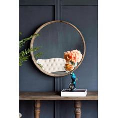 a mirror sitting on top of a wooden table next to a vase with flowers in it