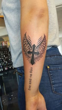 a person with a cross and wings tattoo on their arm