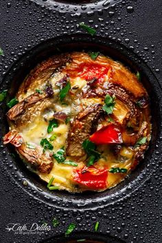 two pans with food in them on top of a black tablecloth and water droplets