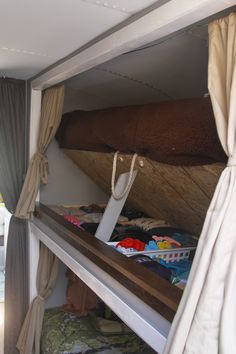 there is a bunk bed in the back of a truck with clothes on it and a bag hanging from the top