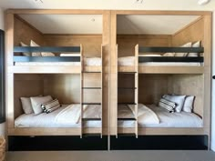 two bunk beds in a room with windows and pillows on the bottom bunk, one is made out of wood