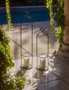 two candles sitting on top of a table next to a pool