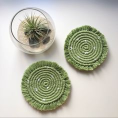 two green coasters sitting on top of a table next to a potted plant