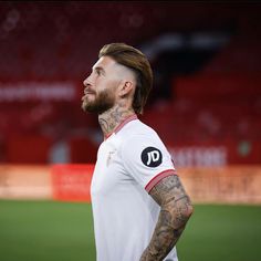 a man with tattoos standing on a soccer field