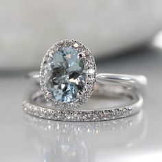 a close up view of a ring with an aqua blue stone in the center and white diamonds surrounding it