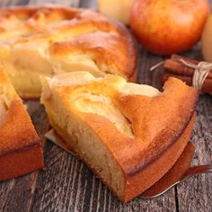 an apple pie is cut into slices on a wooden table with apples and cinnamon sticks