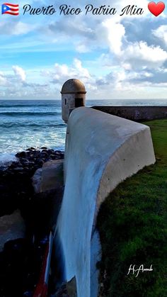 there is a water fall coming out of the side of a wall next to the ocean