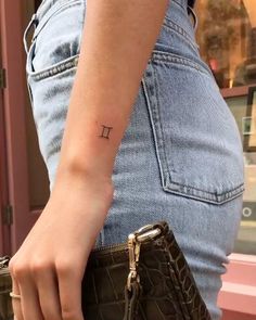 a woman with a small tattoo on her arm holding a purse and looking at the camera