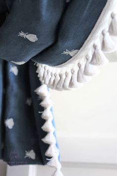 a blue and white curtain with tassels hanging from it