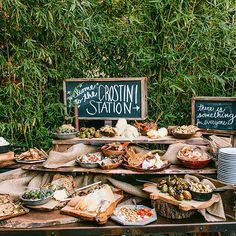 a table filled with lots of food on top of wooden trays next to green plants