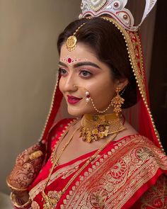 a woman wearing a red and gold bridal outfit with a crown on her head