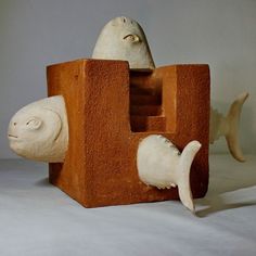 a clay sculpture of a cat and fish in a wooden box with white paint on it