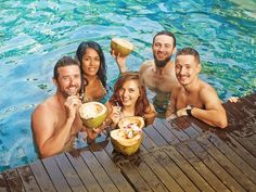 a group of people sitting around a pool drinking coconuts and having drinks in the water