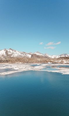 the blue water is surrounded by snow covered mountains