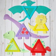 colorful paper cut outs with different shapes and sizes on white wooden boards, including dinosaurs