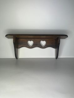 a wooden shelf with two hearts on it's sides, against a white wall