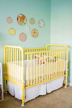 a yellow crib in a blue room with plates on the wall