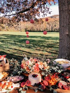 an outdoor picnic with food on the table and paper lanterns hanging from trees in the background