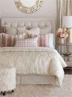 a bedroom with a bed, pillows and a mirror on the wall above it's headboard