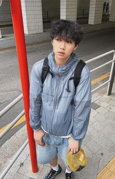 a young man standing next to a red pole