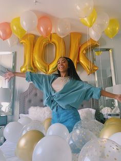 a woman standing in front of balloons that spell out the word joy with her arms outstretched