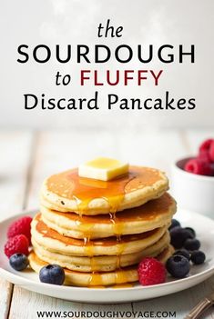 a stack of pancakes with syrup on top and berries in the foreground text reads, the sourdough to fluffy discard pancakes